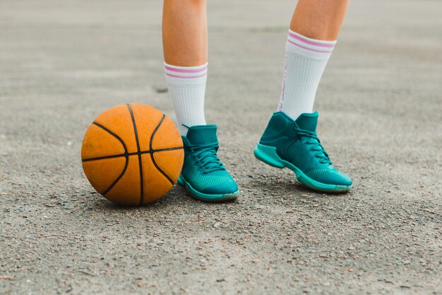 Pallacanestro accanto alle scarpe della ragazza