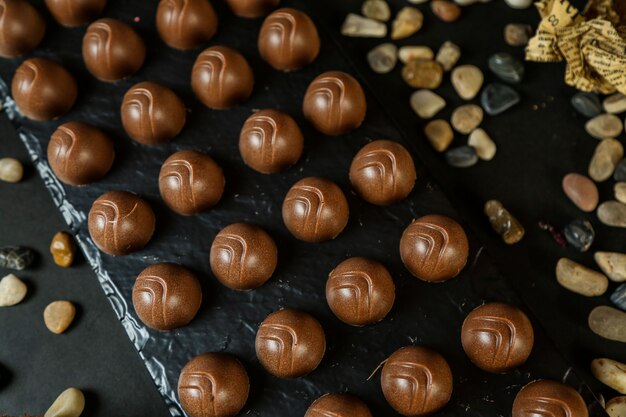 Palle del cioccolato nella vista laterale delle pietre nere della carta del bordo