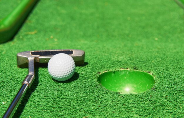 Pallina da golf e mazza da golf su erba artificiale.