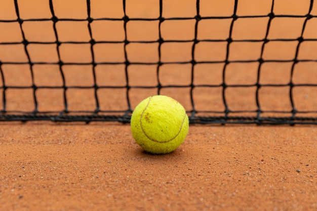 Pallina da tennis del primo piano accanto a rete