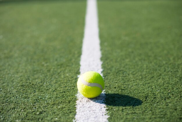 Pallina da tennis del primo piano su una linea di un campo da tennis