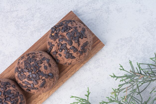 Palline di biscotti al cioccolato su una tavola accanto al ramo di pino, sul tavolo di marmo.