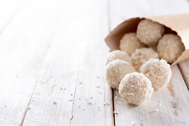 Palline di cocco fatte in casa su un tavolo di legno bianco