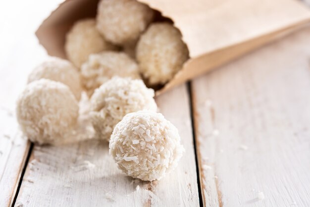 Palline di cocco fatte in casa su un tavolo di legno bianco