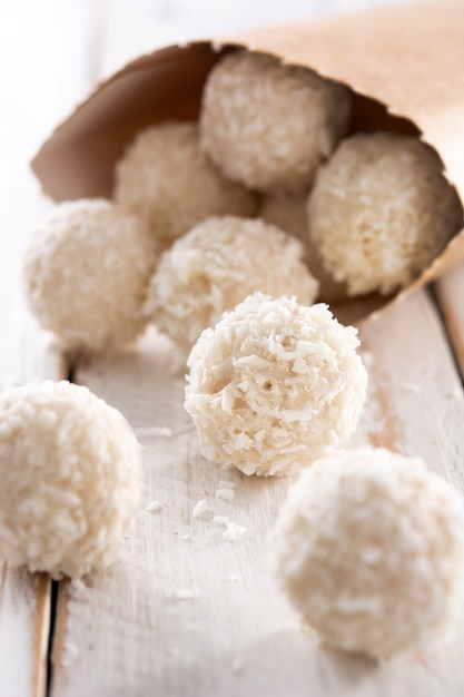 Palline di cocco fatte in casa su un tavolo di legno bianco