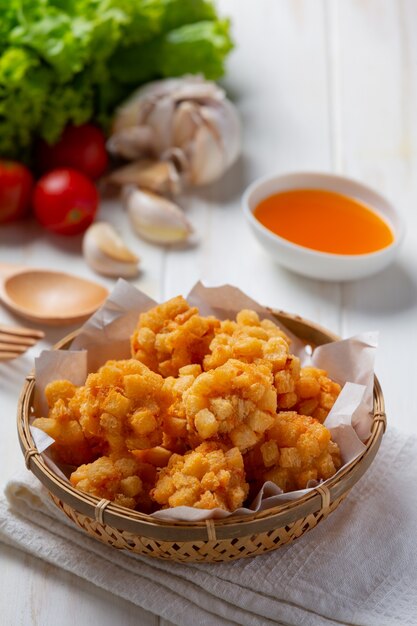 Palline di gamberetti ricoperte di fritto impanato sulla superficie in legno bianco.