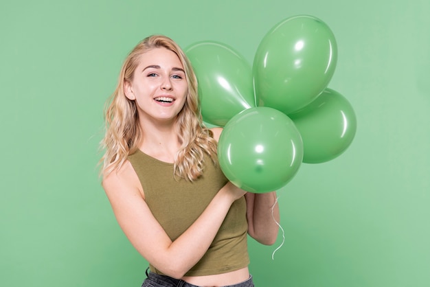 Palloncini azienda giovane donna e guardando il fotografo