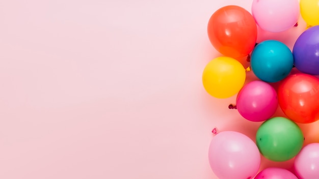 Palloncini colorati gonfiati su sfondo rosa con spazio per la scrittura del testo