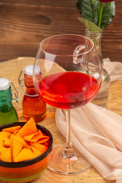 Palloncini di vetro di vino con palloncino vista dal basso in una ciotola di bottiglie rosse e verdi su superficie marrone