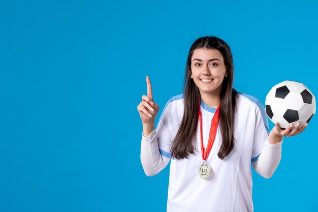 Pallone da calcio femminile della tenuta di vista frontale giovane sulla parete blu