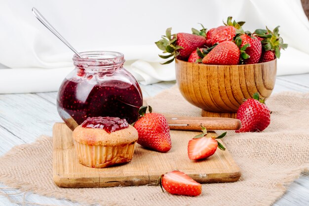 Pancake di vista laterale con la fragola e il coltello freschi dell'inceppamento di fragola su fondo bianco