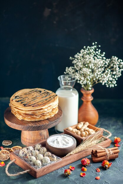 Pancake gustosi vista frontale con noci e latte su superficie blu scuro