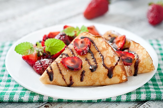 Pancakes con fragole e cioccolato decorati con foglie di menta