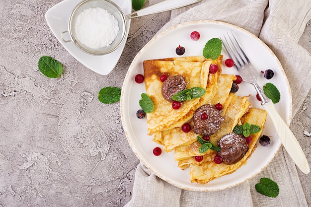 Pancakes con frutti di bosco e cioccolato decorati con foglie di menta. Gustosa colazione Vista dall'alto