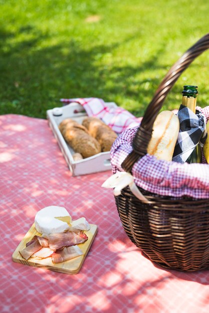 Pancetta e formaggio sul tagliere sopra il panno con cestino da picnic