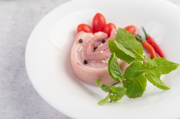 Pancia di maiale in un piatto bianco con semi di pepe Pomodori e spezie.