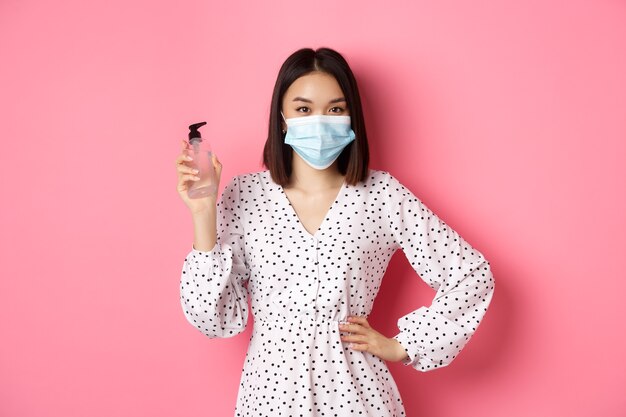 Pandemia di Covid e concetto di stile di vita bella donna coreana in abito e maschera medica che mostra la mano s...