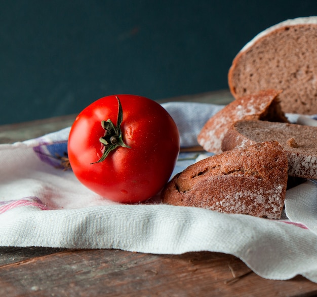 Pane a fette con un pomodoro intero su un canovaccio bianco.