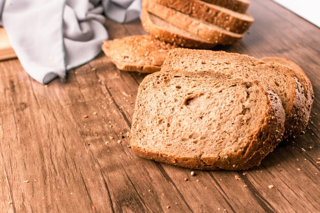 Pane affettato del pane tostato su una tavola di legno sull'asciugamano blu