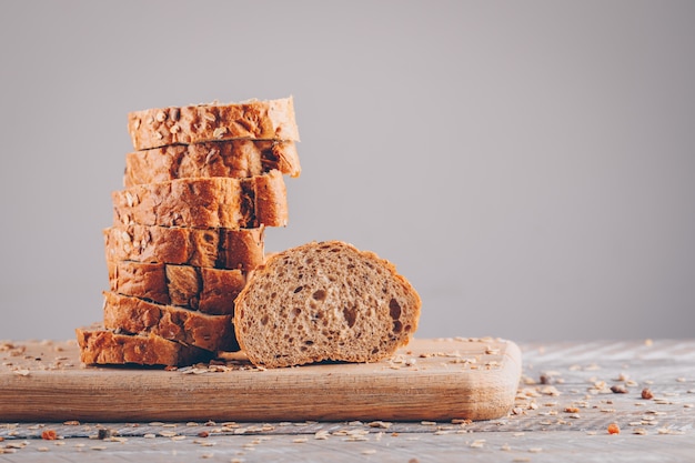 Pane affettato in una vista laterale del tagliere su una tavola di legno e su una superficie grigia