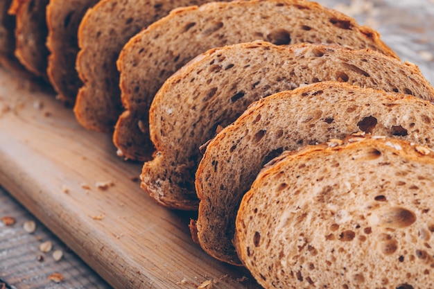 Pane affettato su un tagliere su una tavola di legno e su una vista laterale di superficie grigia.