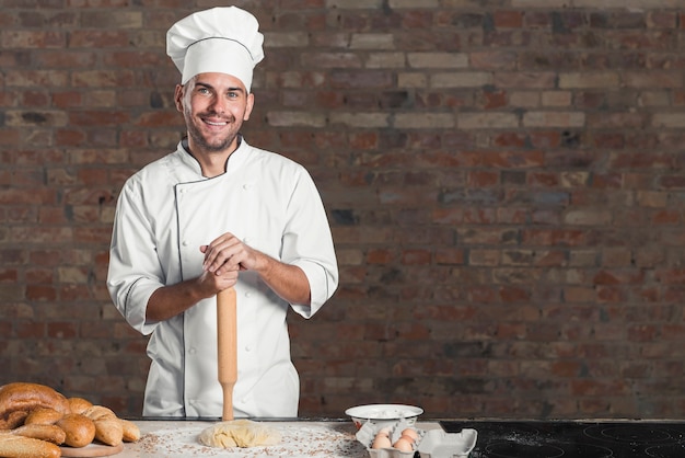 Pane al forno sorridente con pasta e ingredienti sul piano di lavoro della cucina