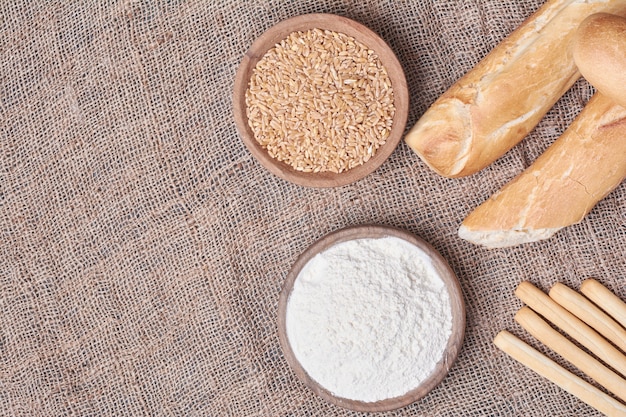 Pane baguette con ingredienti sul tavolo blu.