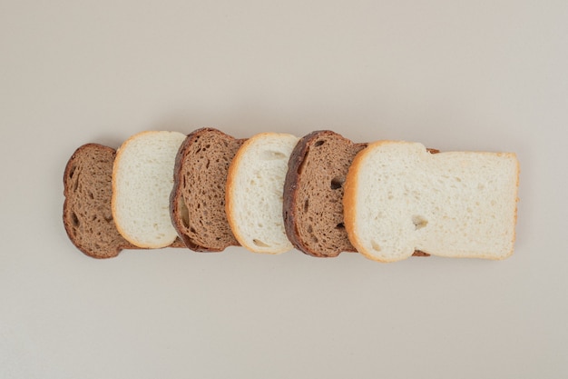 Pane bianco e marrone fresco affettato sulla superficie bianca