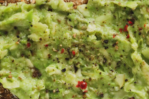 Pane croccante appetitoso gustoso con purè di avocado servito sul piatto. Avvicinamento.