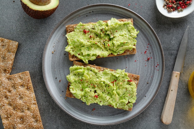 Pane croccante appetitoso gustoso con purè di avocado servito sul piatto.