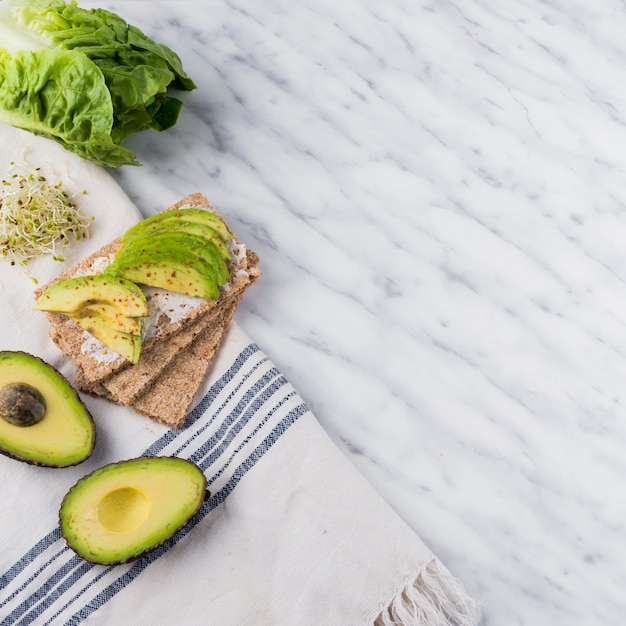 Pane croccante con avocado affettato sul tavolo di marmo