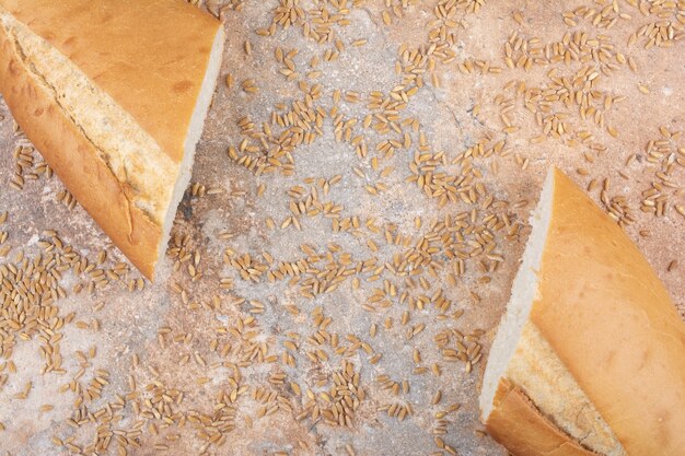 Pane di grano tagliato a metà con orzo su superficie di marmo