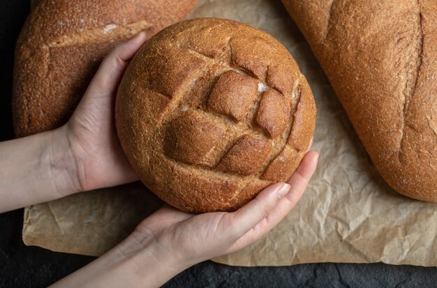 Pane di pagnotte diverse. Donna che tiene con la mano.