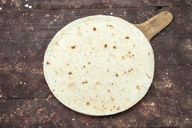 Pane di pasta lavash rotondo vista dall'alto come sulla pasta sfoglia di farina di cibo da scrivania in legno marrone