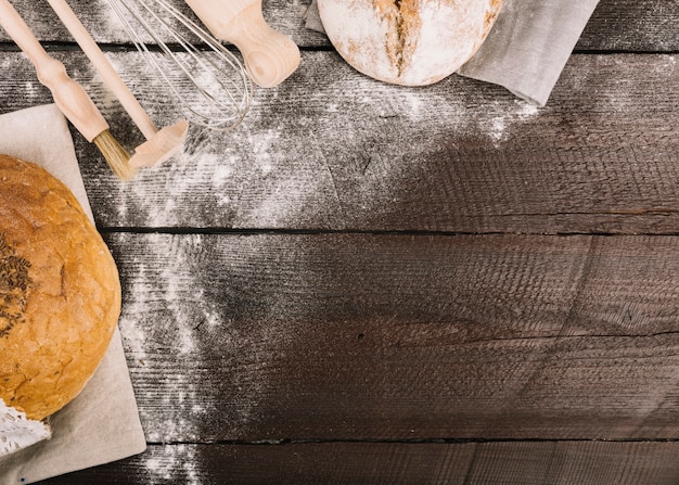 Pane e utensili da cucina spolverati di farina sulla tavola di legno