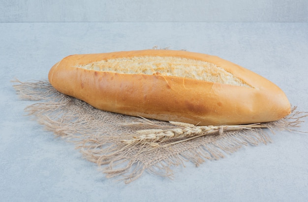 Pane fresco della pagnotta su tela da imballaggio con grano. Foto di alta qualità