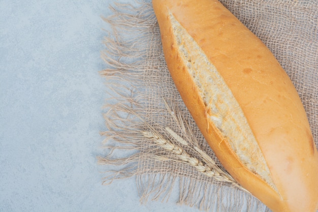 Pane fresco della pagnotta su tela da imballaggio con grano. Foto di alta qualità