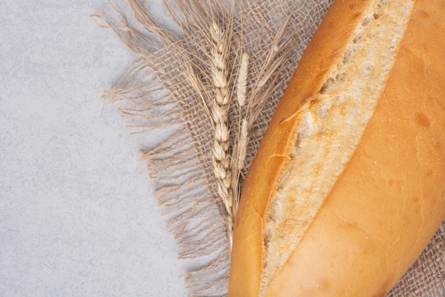 Pane fresco della pagnotta su tela da imballaggio con grano. Foto di alta qualità