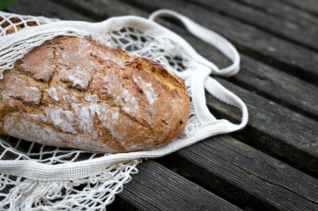 Pane fresco in una borsa della spesa su un fondo di legno