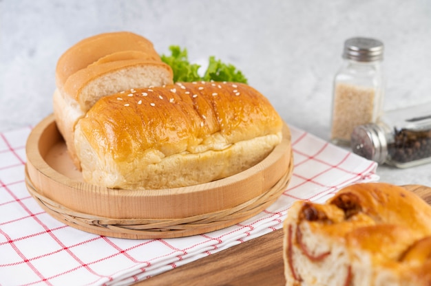 Pane in un vassoio di legno su un panno rosso e bianco.