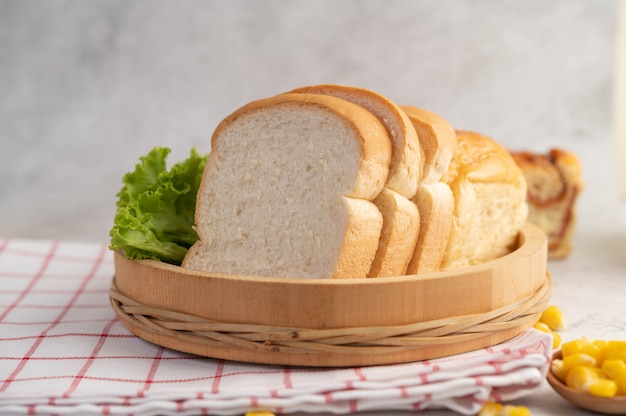 Pane in un vassoio di legno su un panno rosso e bianco.