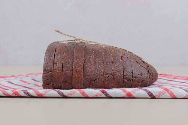 Pane integrale fresco affettato in corda sulla tovaglia. Foto di alta qualità