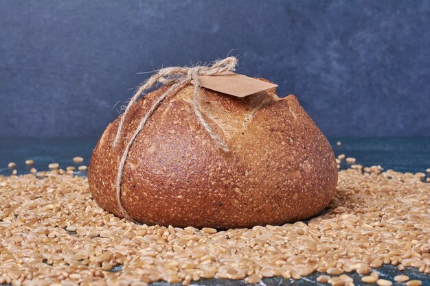 Pane nero sui chicchi di grano sulla tavola blu.