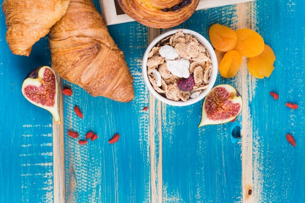 Pane per croissant; frutto di fico; corn flakes e albicocca secca su sfondo con texture in legno