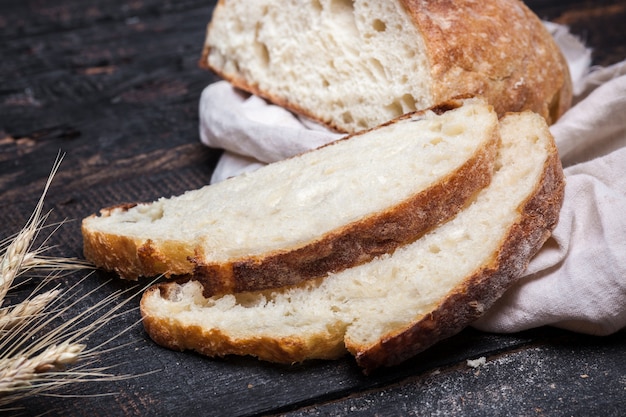 Pane rustico sul tavolo di legno. Sfondo scuro lunatico con spazio di testo libero.