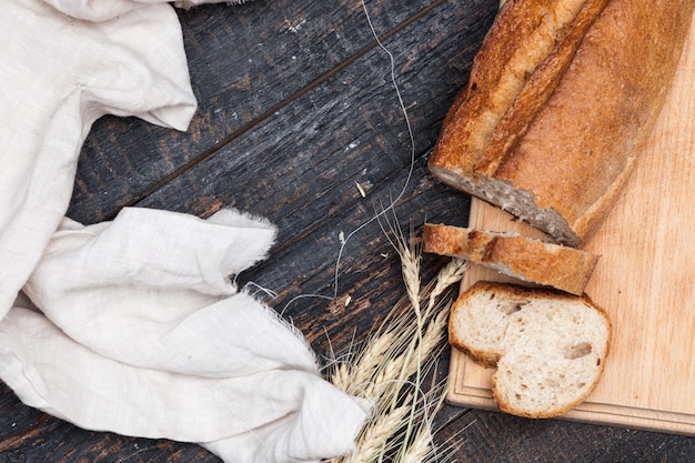 Pane rustico sulla tavola di legno con grano e panno