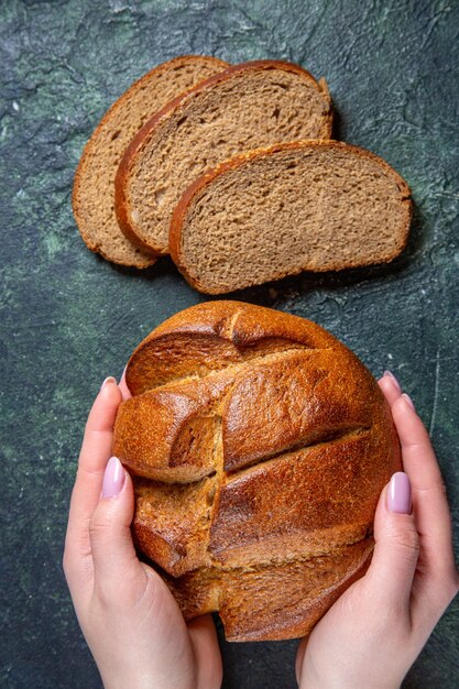 Pane scuro fresco di vista superiore con le mani femminili sulla scrivania scura