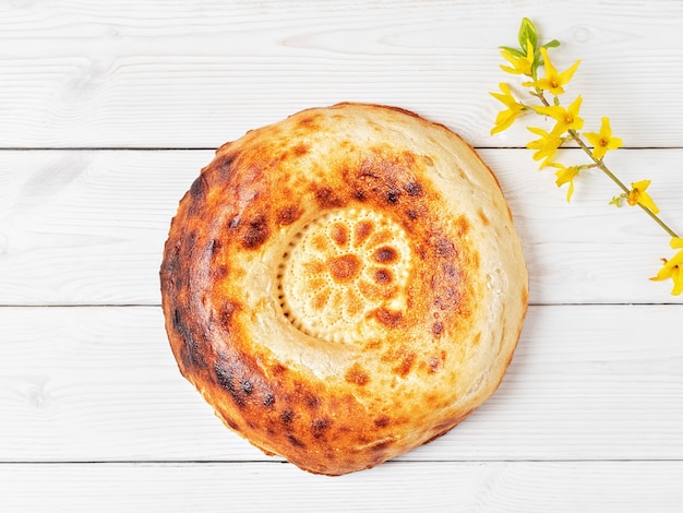 Pane tandoor rotondo fresco gustoso su un tavolo di legno bianco