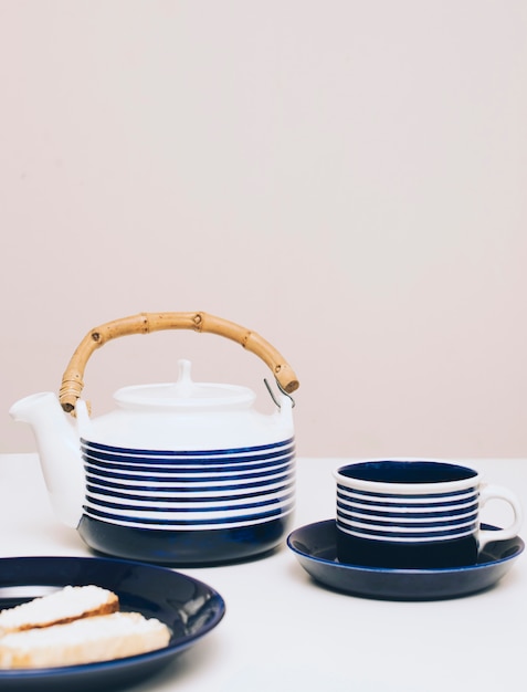 Pane; teiera e tazza di caffè sulla scrivania su sfondo colorato