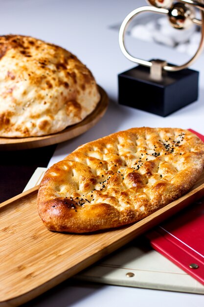 Pane tenero fresco cosparso di semi di sesamo su una tavola di legno